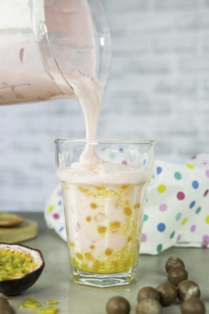 Strawberry shake being poured over passion fruit popping boba